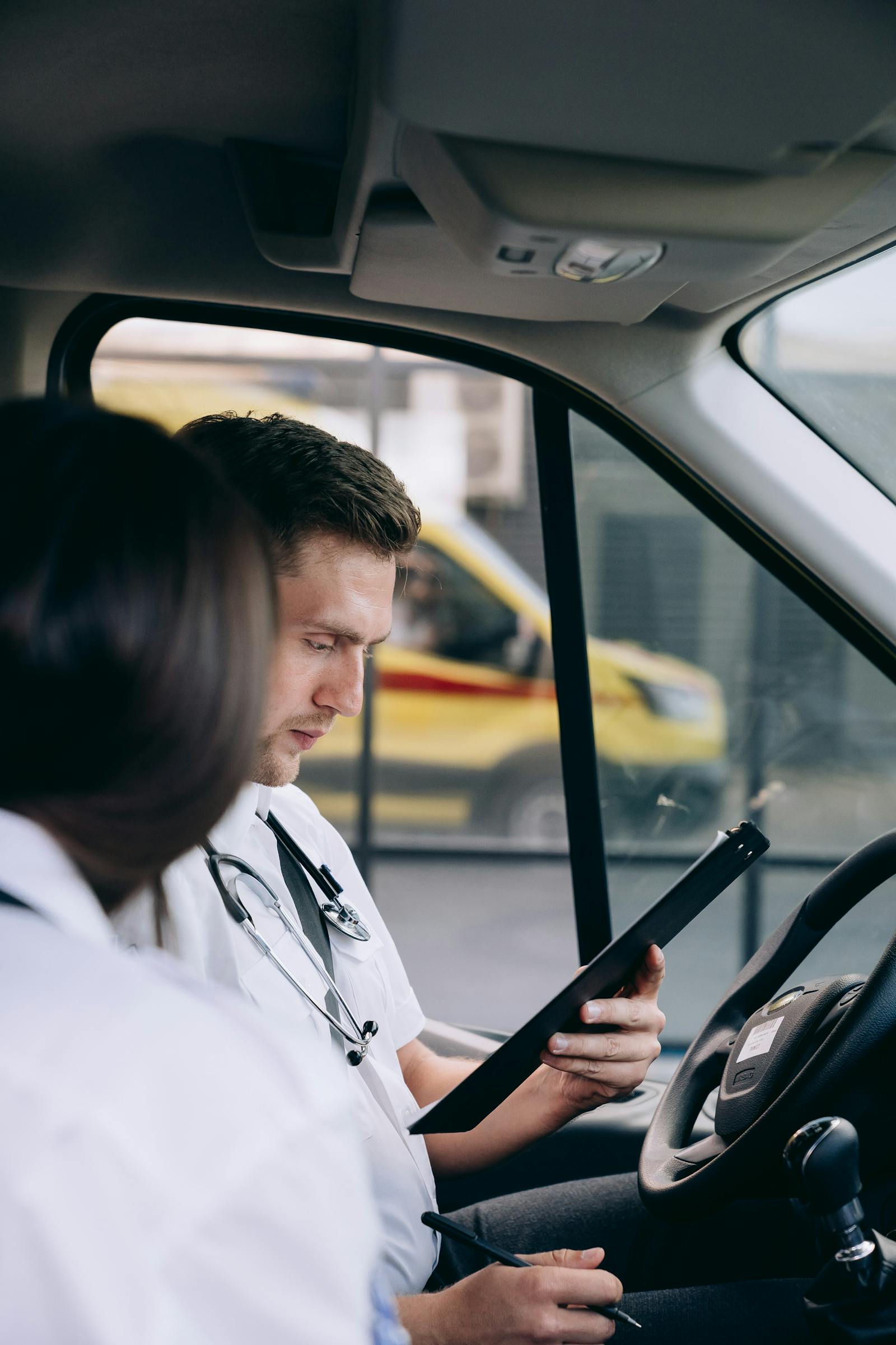 EMS trainees reviewing a tablet inside an ambulance during refresher instruction.